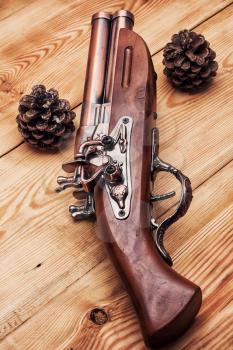 Old hunting musket on a light wooden background with forest cones