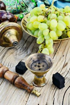 Still life with smoking hookah and grapes on wooden background