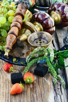 Still life with smoking hookah and grapes on wooden background