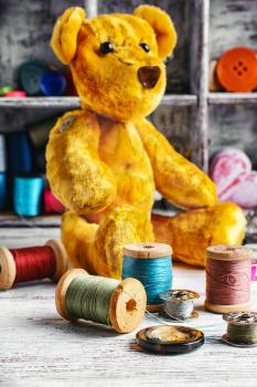 Made by hand toy bear on the background of tools for needlework