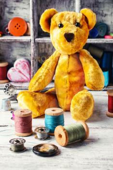 Made by hand toy bear on the background of tools for needlework