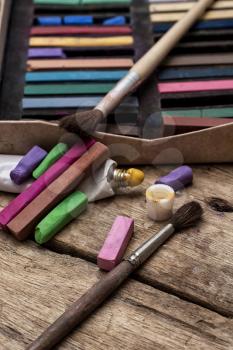 Crayons and paints for painting on wooden background