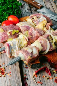 raw meat with vegetables threaded onto a skewer for roasting on the coals