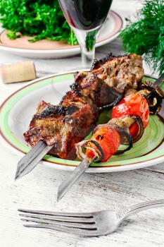 Beef cooked with vegetables on skewers and glass of wine