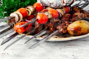 Beef cooked with vegetables on skewers and baked potatoes