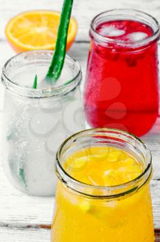 Three bottles of drinks from aloe,orange, and cranberries in a light tone