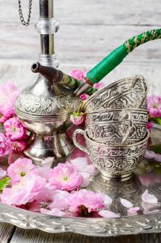 Stylish metal Arabic hookah, and small flowers of wild rose