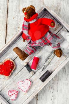 Soft toy teddy bear in clothes and sewing equipment