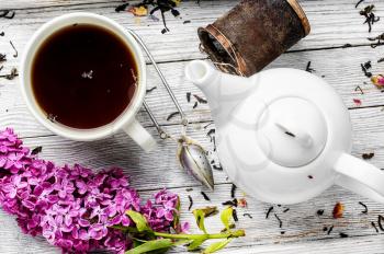 Cup of herbal medicinal tea kettle and bunch of lilac blossoms