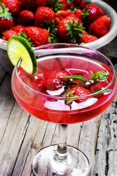 alcohol cocktail in glass on a long stalk with strawberries and lime
