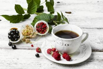 Mug with fragrant summer tea with fruits of raspberry and currant