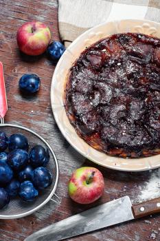Apple pie with apples and plums in rustic style