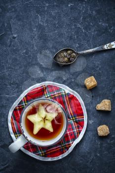 Cup of tea with apple star on slate blue background