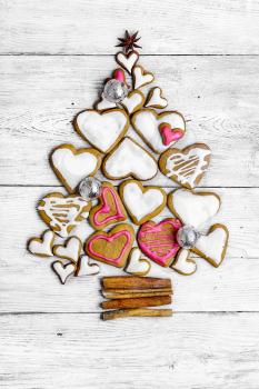 Christmas cookies are laid out in the shape of Christmas tree on light wooden background