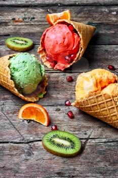ice-cream cone with kiwi fruit and tangerines on wooden background