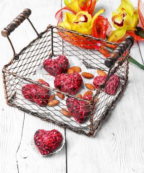 Stylish metal basket with candies in shape of heart and bouquet of orchids