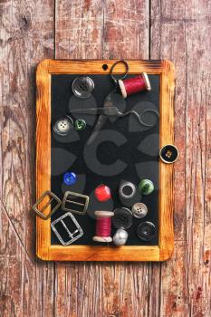 Set of buttons and sewing thread on the chalk board for drawing