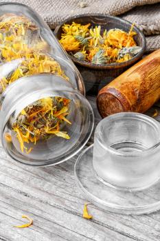 Glass pharmacy jar with dried flowers of calendula for therapy