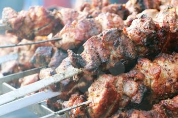 Rosy delicious shish kebab barbecue meat on skewers in smoke. Hot grill food
