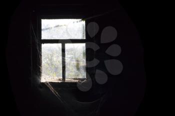 Old dirty window with cobweb around and darkness inside