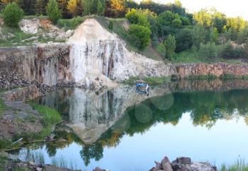 Basalt columns pile rock quarry. Beautiful stone landscape and submerged excavator in water