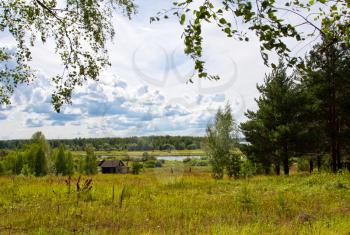 Rural sunny landscape with wooden house near the river