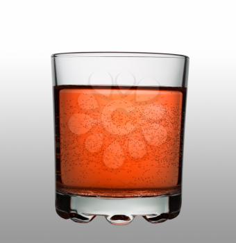 Glass with red fizzy cocktail on gradient background, studio shot