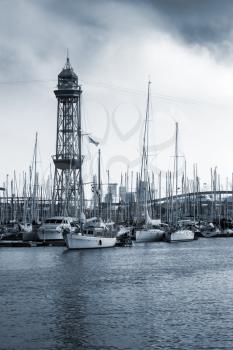 Port of Barcelona, Spain. Yachts, boats and old big tower. Monochrome vertical photo
