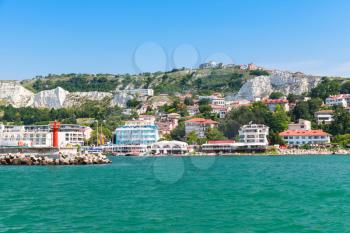 Coastal landscape of Balchik resort town. Entrance to port, red lighthouse on the pier. Coast of the Black Sea, Varna region, Bulgaria