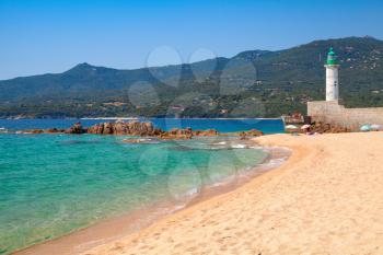 Sandy beach and lighthouse tower. Coastal landscape of Propriano town, Corsica island, France