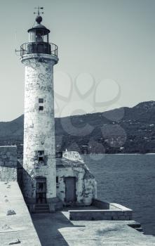White lighthouse tower. Entrance to Propriano port, Corsica island, France. Monochrome toned, retro stylized photo