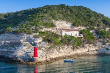 Cliff with old building and red lighthouse, entrance to the port of Bonifacio, Corsica island, France