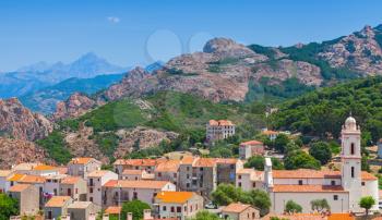 Corsican village landscape, old stone houses with red tile roofs over mountains background. Piana, South Corsica, France