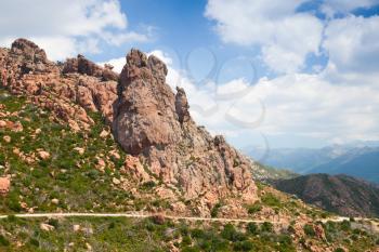 Landscape of South Corsica with turning mountain road and mountains under cloudy sky