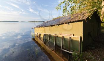 Small green wooden boat garage on the coast of Saimaa lake, typically construction for Finland