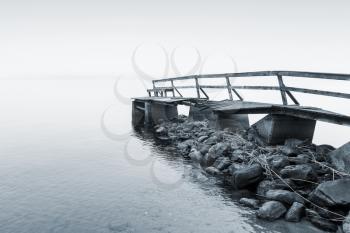Old wooden pier on the lake in foggy morning