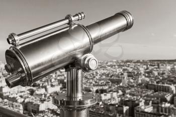 Shining metal telescope mounted on the railings of Eiffel Tower in Paris