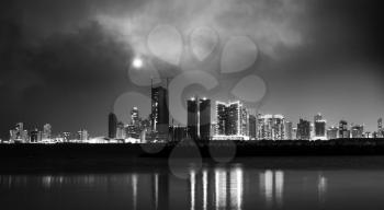 Black and white photo. Night modern city skyline with shining moon. Manama, the Capital of Bahrain, Middle East