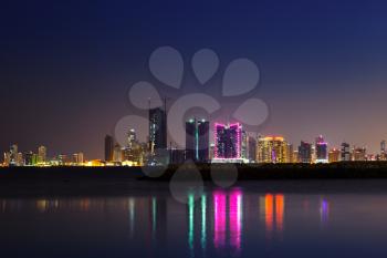 Night modern city skyline with shining lights and reflections in the water. Manama, the Capital of Bahrain, Middle East