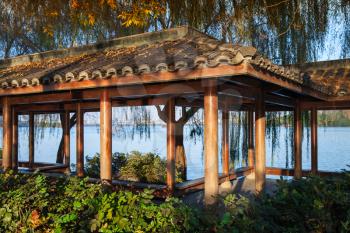 Wooden traditional Chinese Gazebo on the coast. Walking around famous West Lake park in Hangzhou city center, China