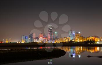 Night city skyline, shining neon lights and reflections in water. Manama, Bahrain, Middle East