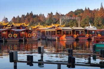 Traditional Chinese wooden recreation boats are moored on the West Lake coast. Famous park in Hangzhou city, China