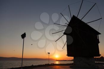 Black silhouette in the morning sun. Old wooden windmill on the coast, the most popular landmark of old Nesebar town, Bulgaria