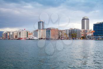 Coastal cityscape with modern buildings under overcast cloudy sky. Izmir city, Turkey