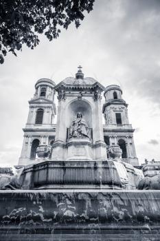 Fountain and facade of Saint-Sulpice, a Roman Catholic church in Paris, France. Black and white vintage stylized photo