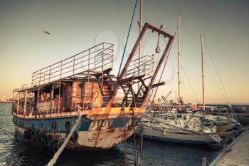 Old rusted pleasure boat is moored in Nesebar, ancient historical town, Bulgaria. Vintage retro stylized photo with tonal correction filter, instagram style 