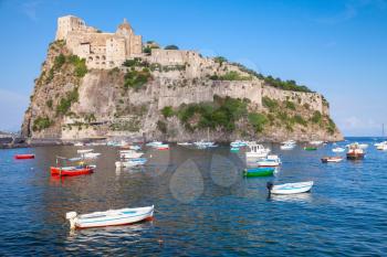 Coastal landscape of Ischia port with Aragonese Castle and anchored wooden boats