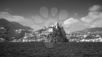 Coastal monochrome landscape of Ischia with Aragonese Castle on rocky island. Mediterranean sea coast, Italy