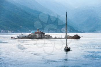 Bay of Kotor. Small island Our Lady of the Rocks and sailing yacht