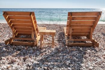 Two wooden sun loungers stand on the Adriatic Sea beach in Montenegro